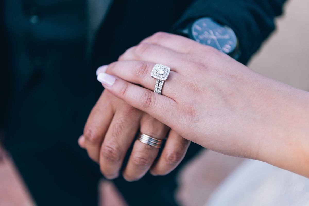 Close up of a hand wearing a diamond engagement ring beside a keyboard at work