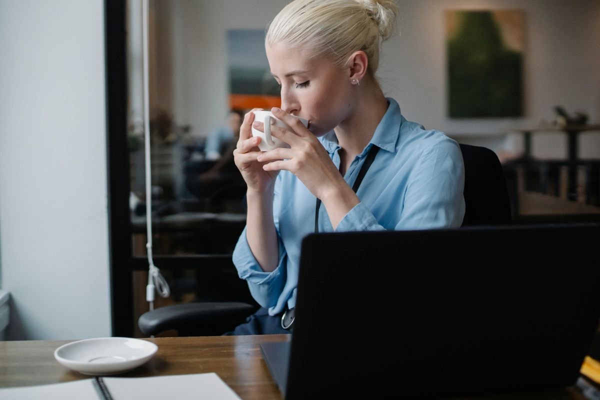Woman taking a coffee break from her laptop instead of wedding planning at her desk
