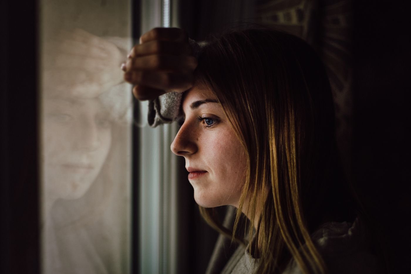 Woman looking out a window deciding if her long distance relationship is worth it