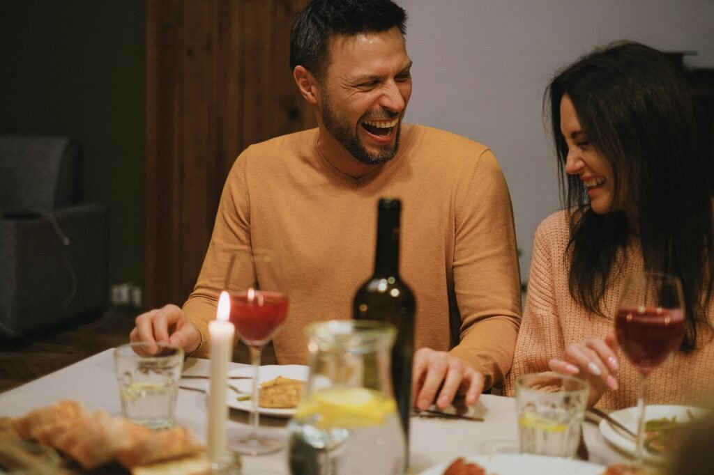 Couple laughing over a shared meal at the dinner table with candles lit
