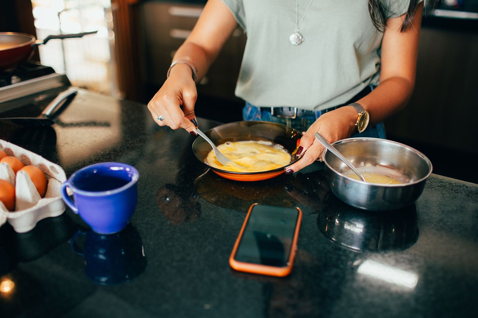 Woman cooking with her phone propped up while talking to her long distance partner