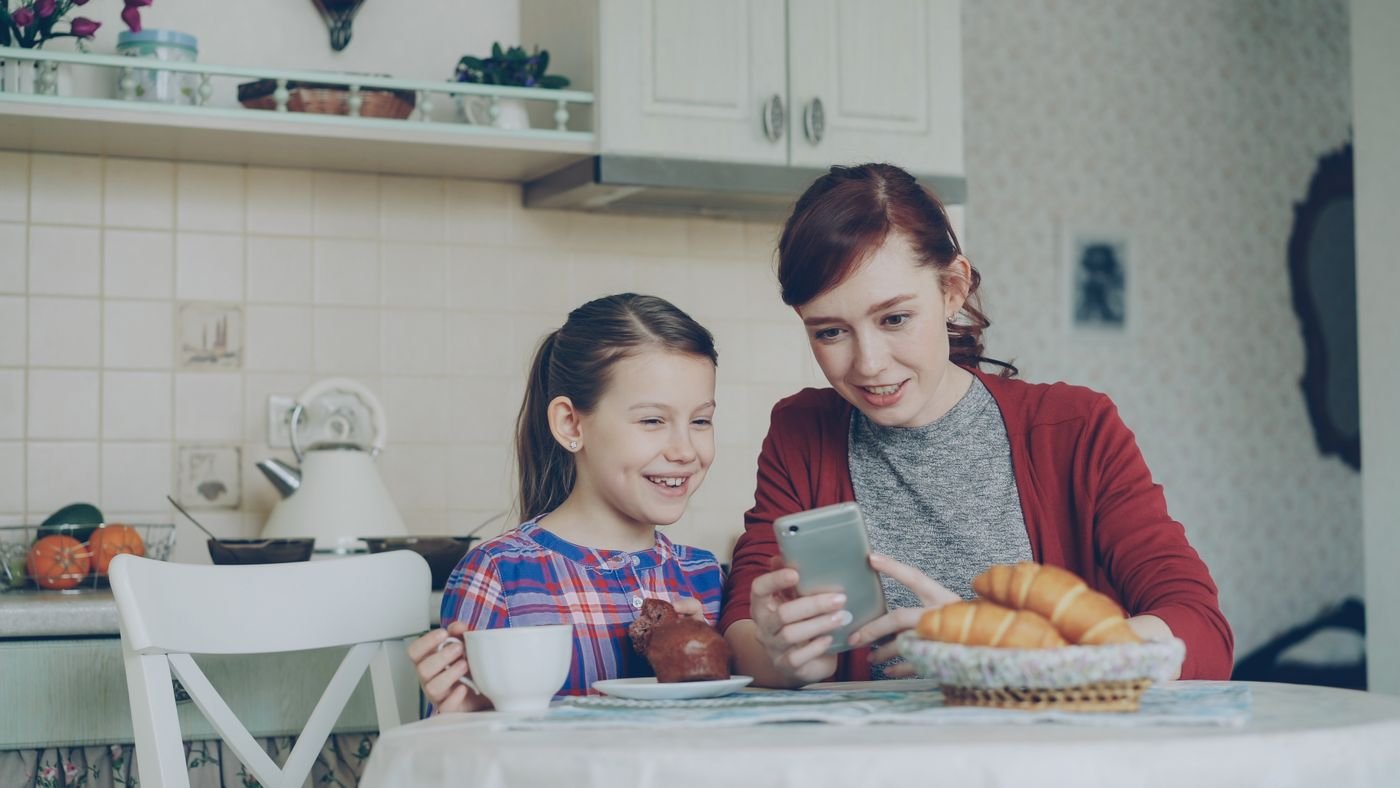 Mother and daughter looking at a phone together while she shares photos of her partner