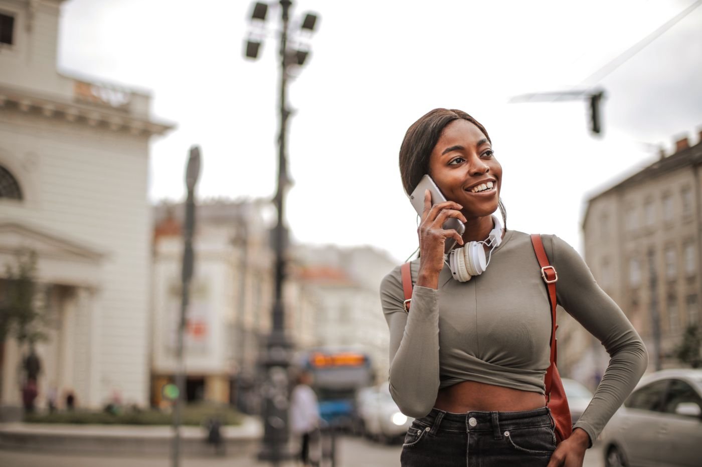 Woman with headphones talking on the phone outdoors, practicing better long distance communication