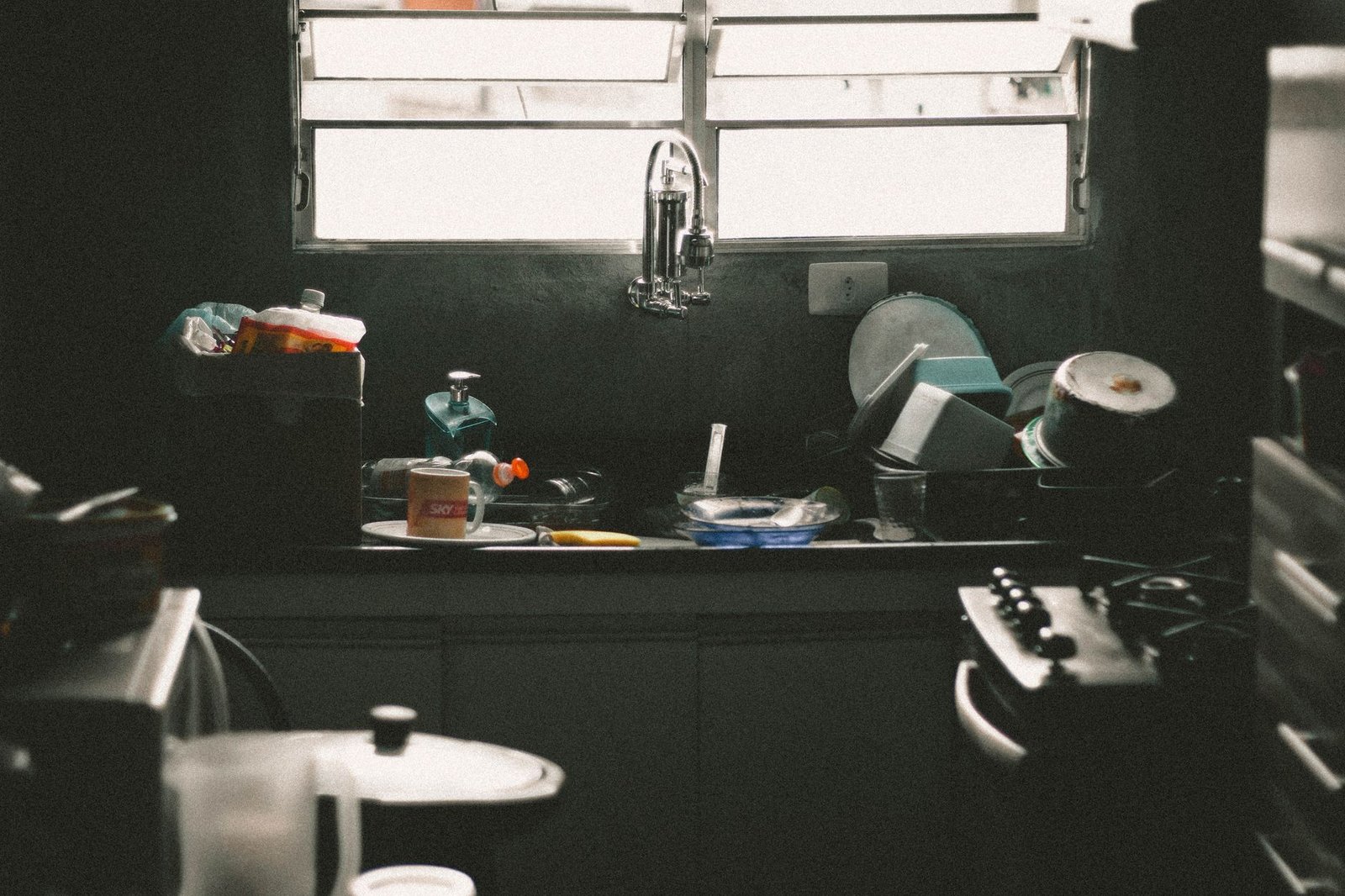 Kitchen sink stacked with dirty dishes left overnight in a messy partner apartment