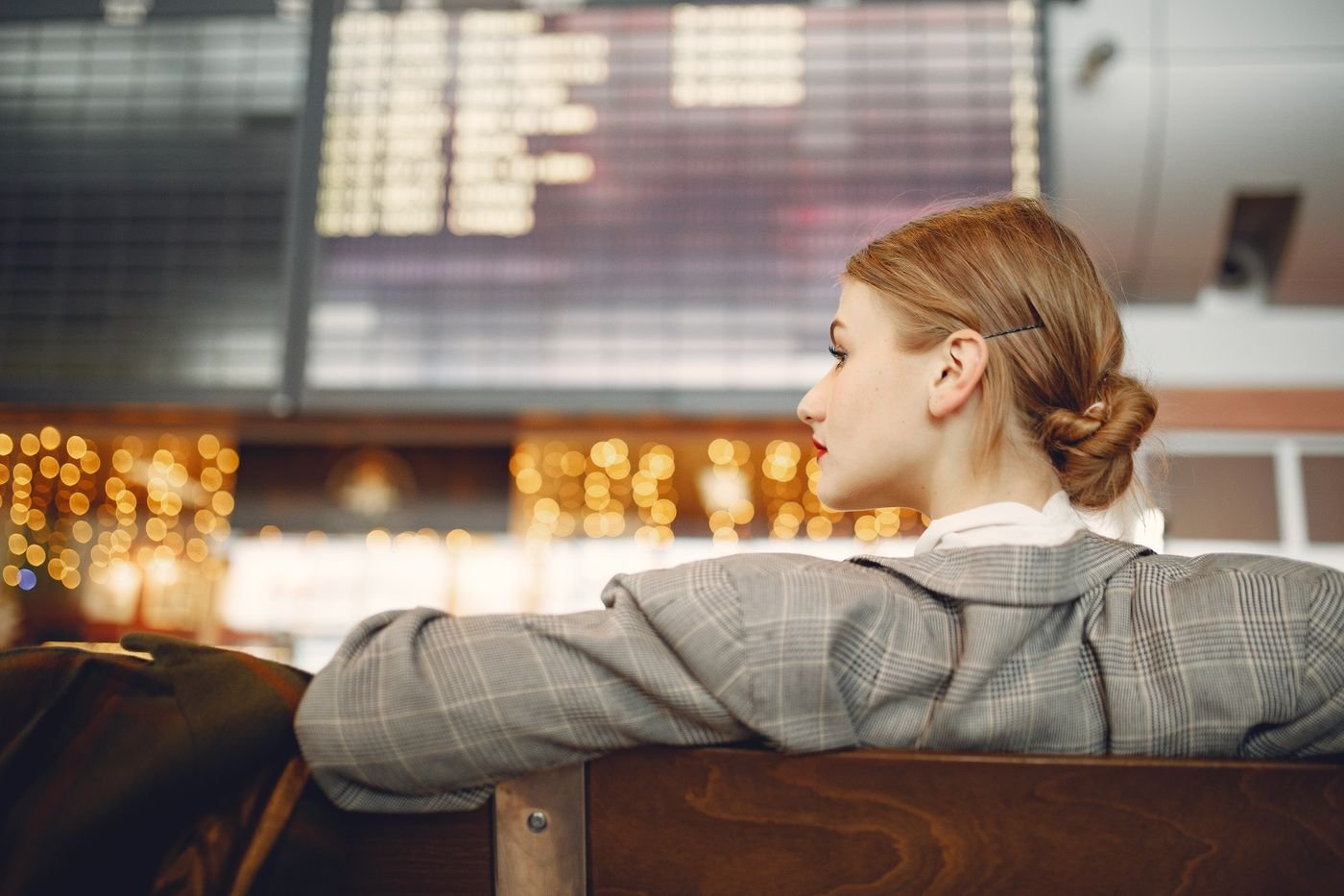 Woman waiting near an airport departure board thinking about her long distance relationship