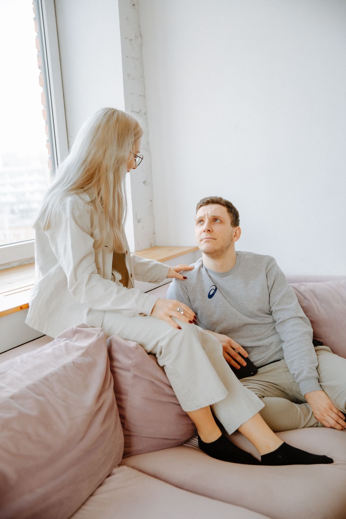 Young couple sitting on a sofa having a vulnerable conversation at home