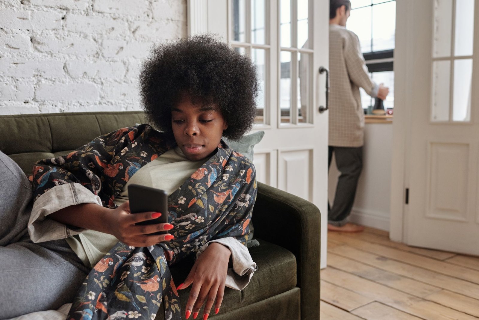 Woman on her sofa rereading a short text message and wondering what it means