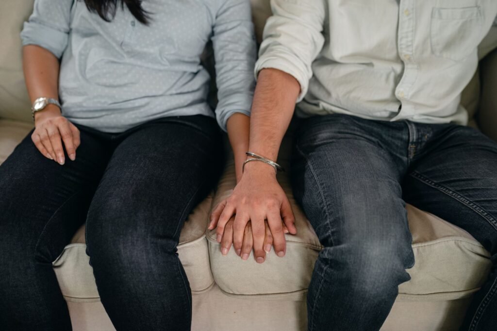 Couple holding hands while talking honestly on the sofa