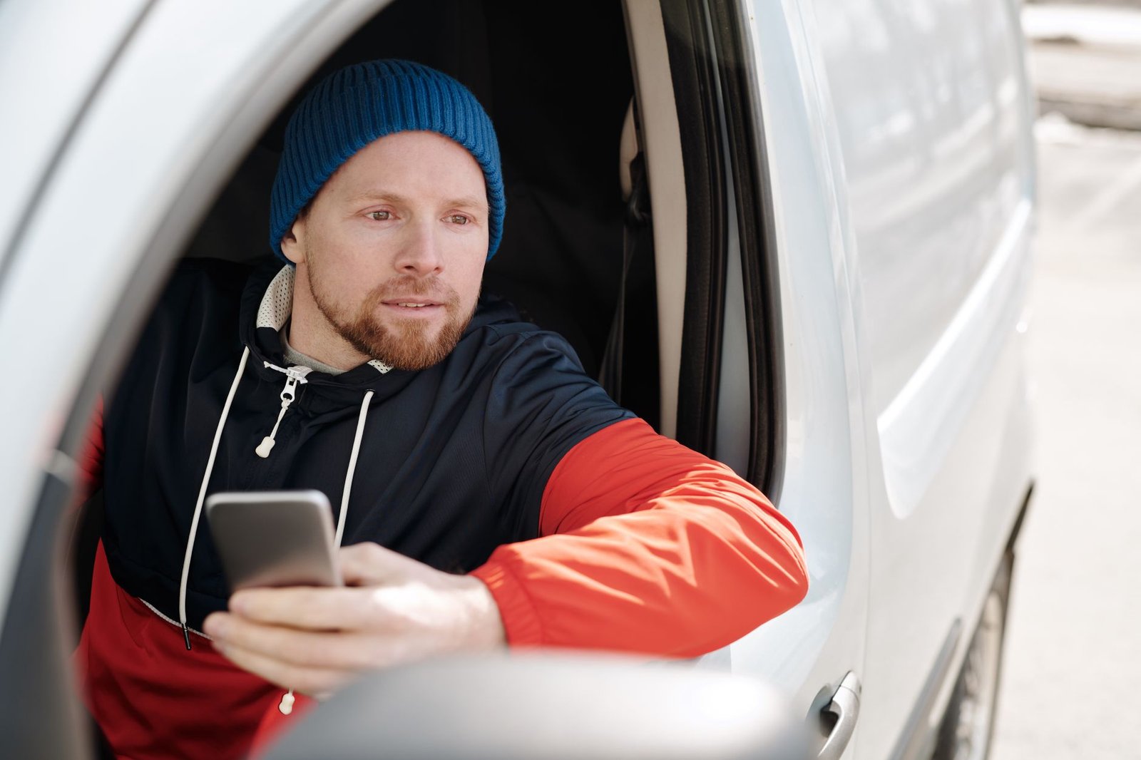 Man looking out a window holding his phone while upset