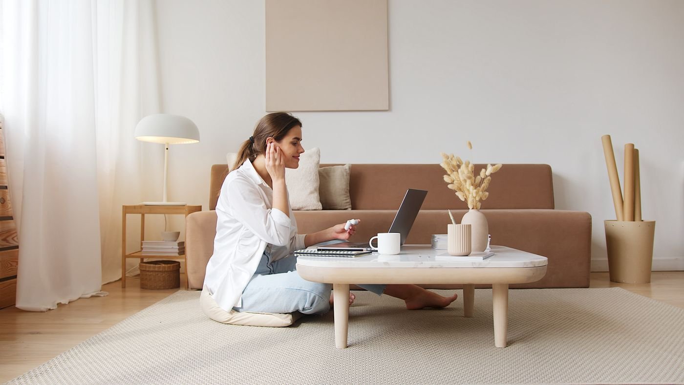 Woman sitting on the floor of her apartment on a video call with her long distance partner