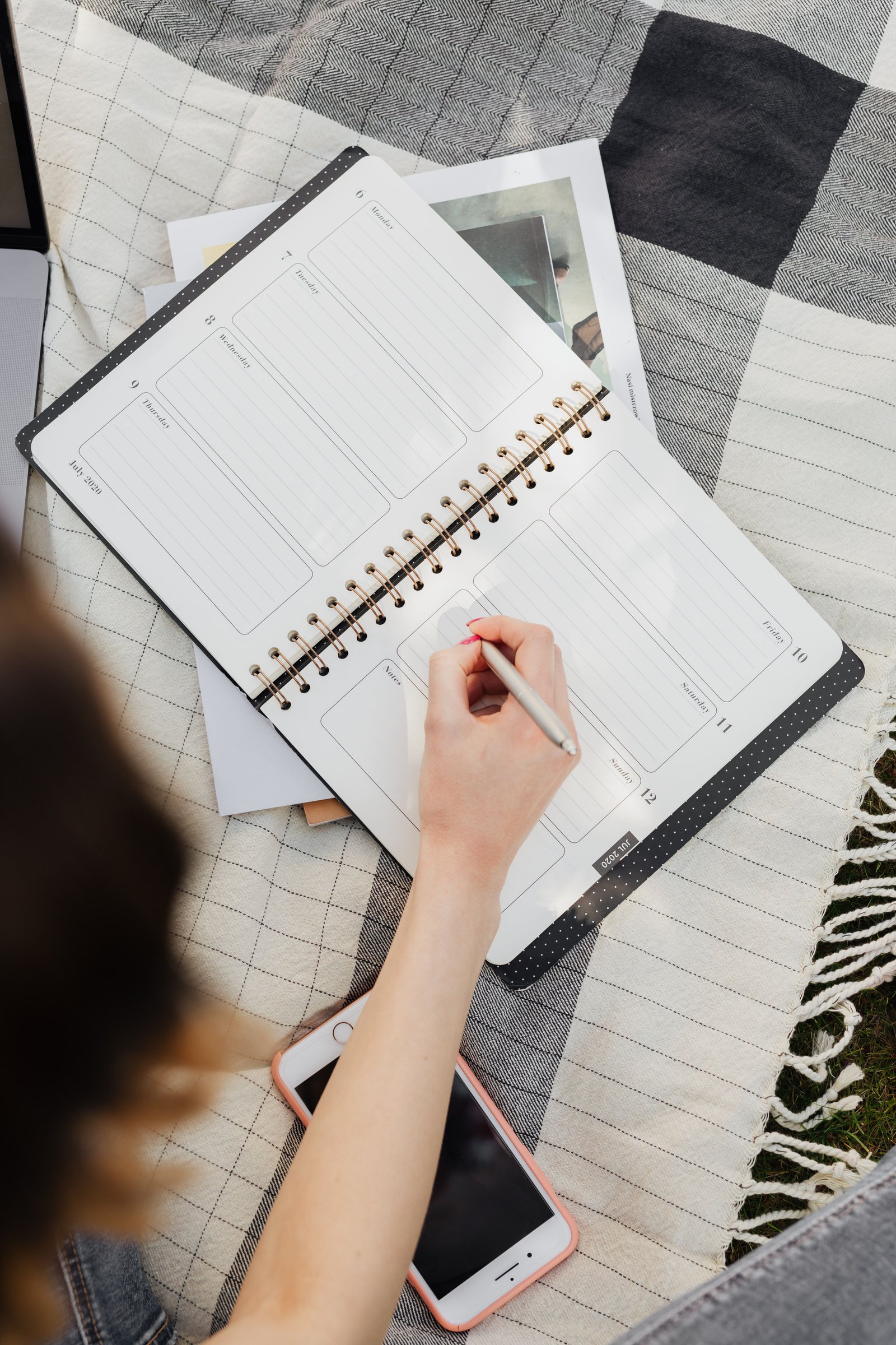 Woman writing a date into a weekly planner at a kitchen table
