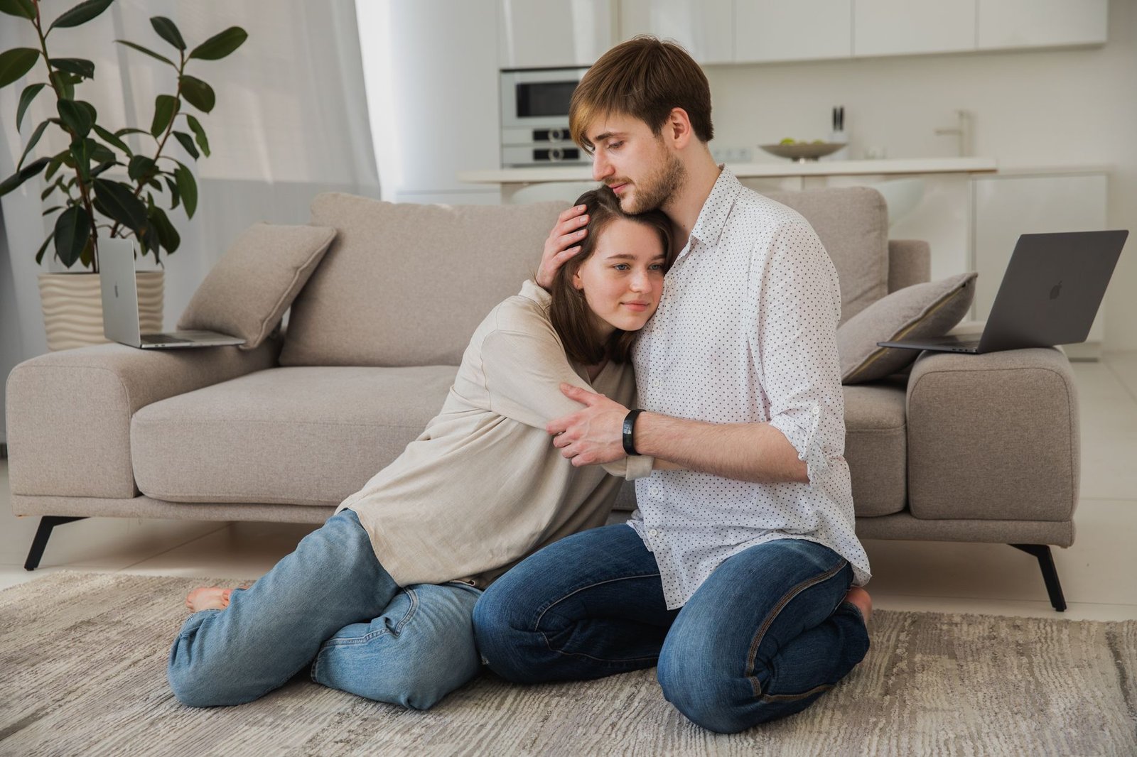 Couple sitting close together on the floor, comforting each other