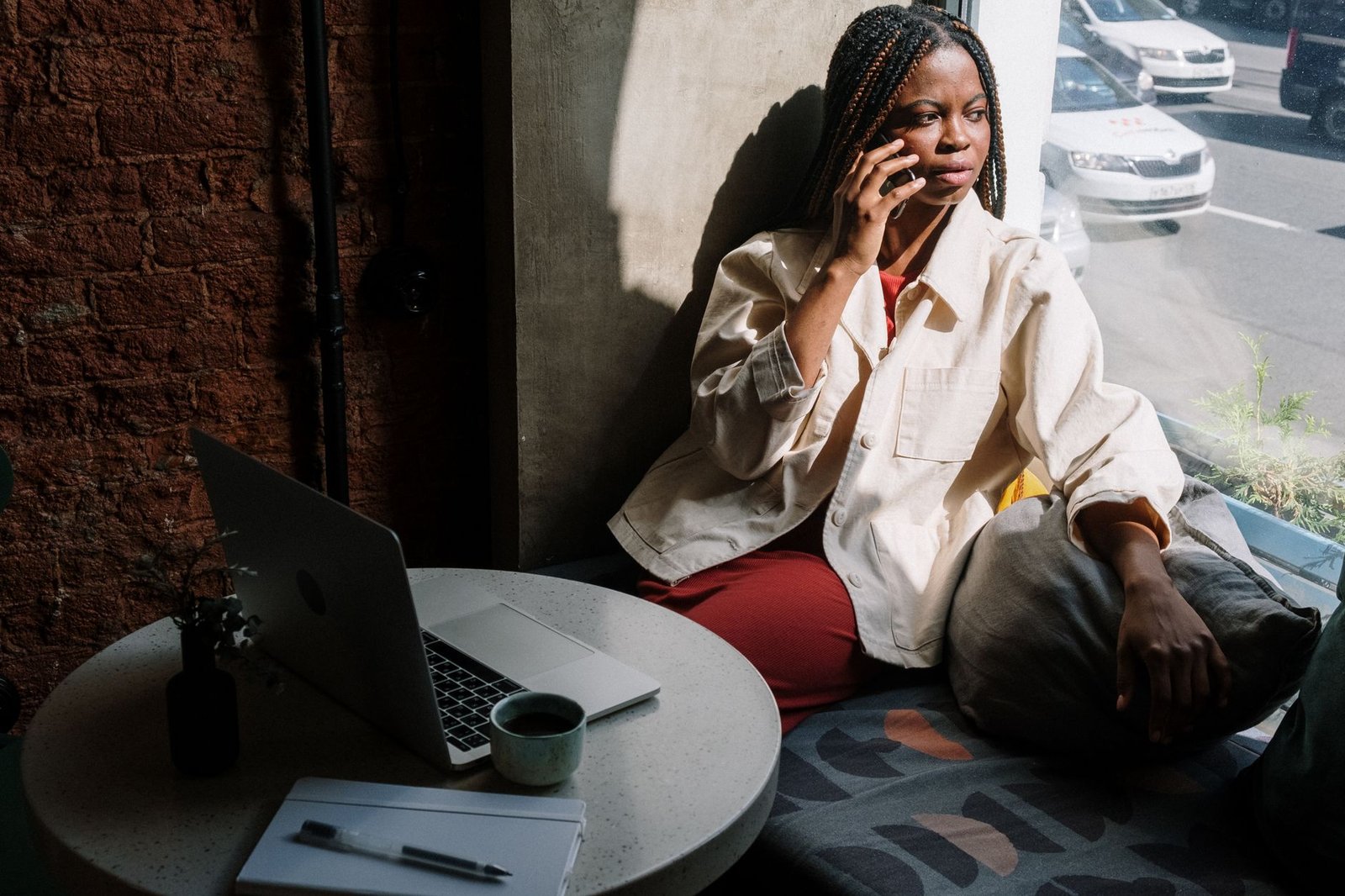 Woman sitting by a window holding her phone while trying to stop overthinking in a long distance relationship