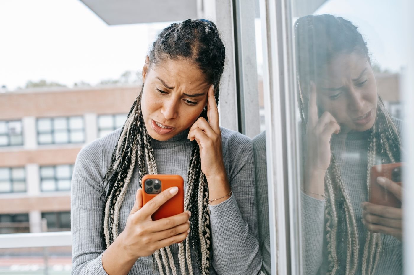 Woman on a balcony staring at her phone waiting for a text from her long distance partner