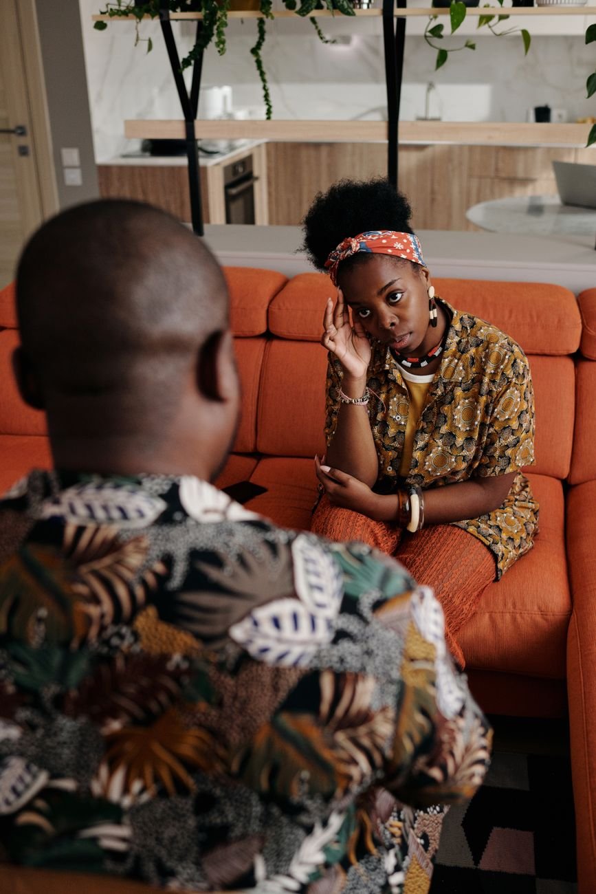 Couple sitting close on a sofa listening to each other without talking