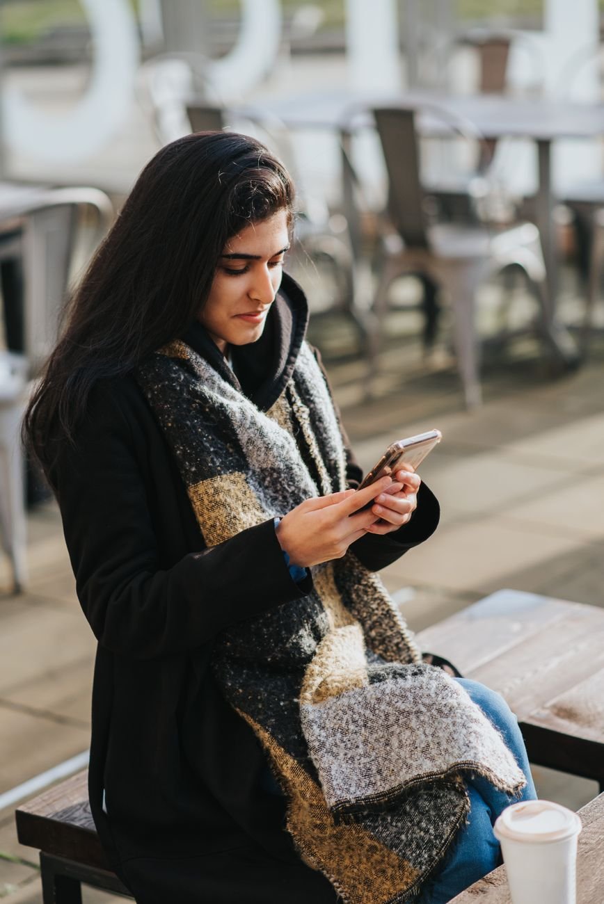 Woman alone at a cafe window checking her phone while he texts all week but never asks her out