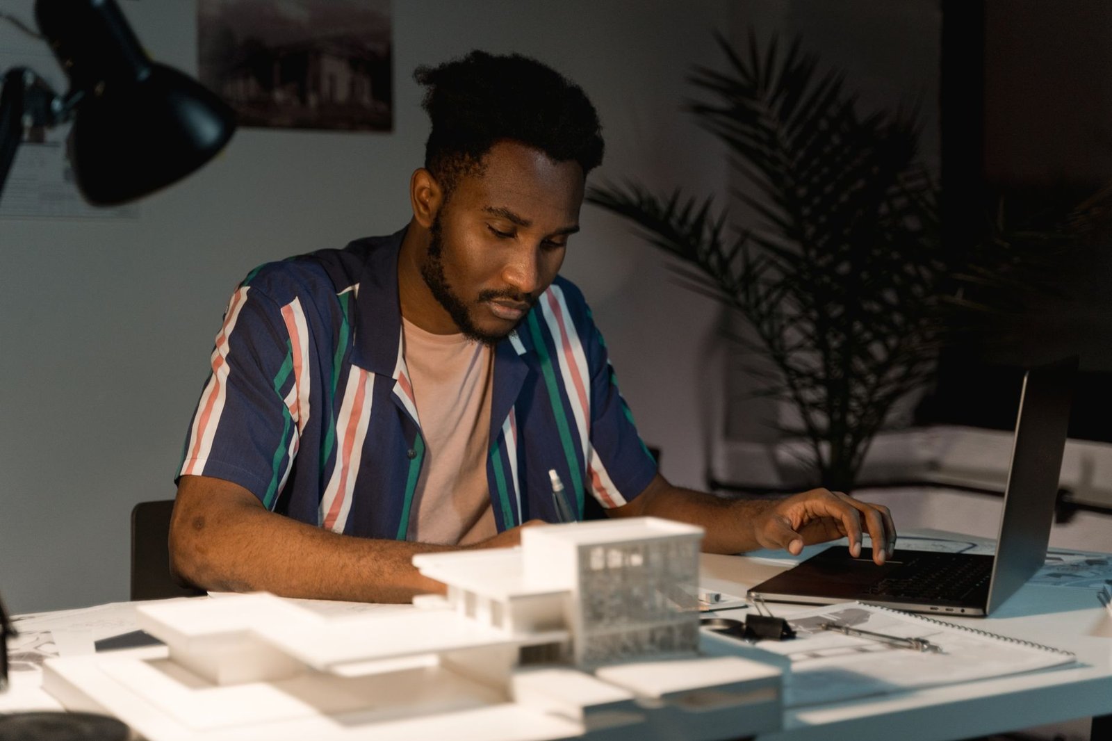 Man working late at night on a laptop surrounded by paperwork