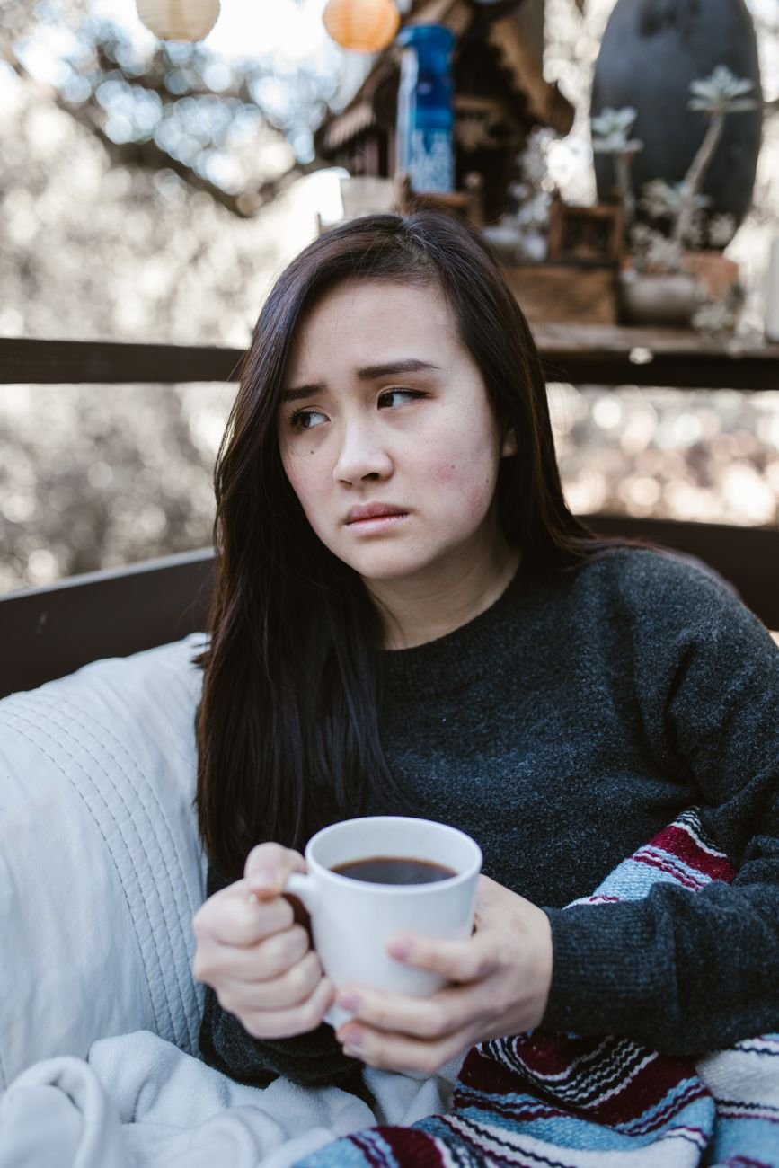 Woman with coffee looking out a window after being ghosted