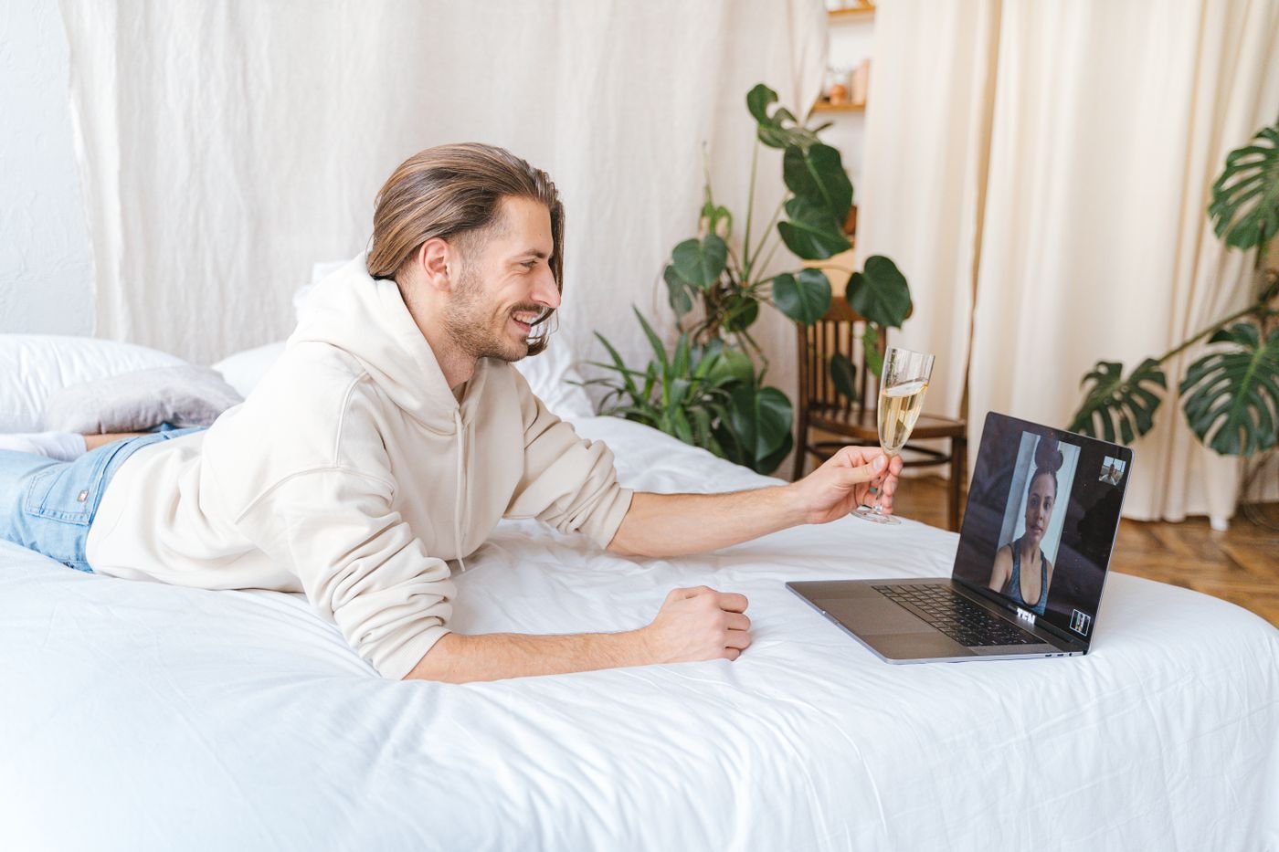 Man smiling on a video call with a glass of wine during a long distance date night