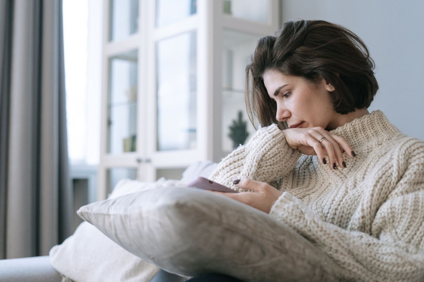 Woman on a couch holding her phone during the hard middle months of a long distance year