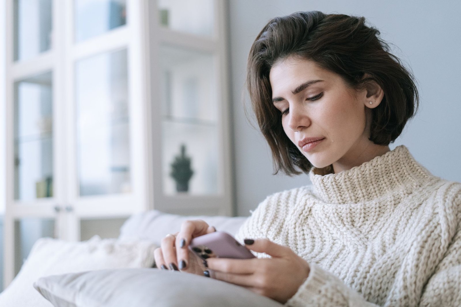 Woman sitting alone scrolling her phone after upsetting news