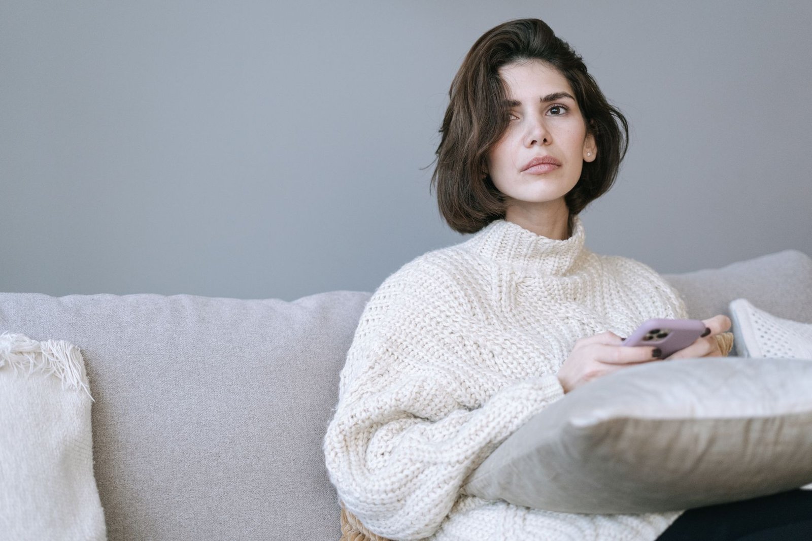 Woman holding her phone looking thoughtful and sad