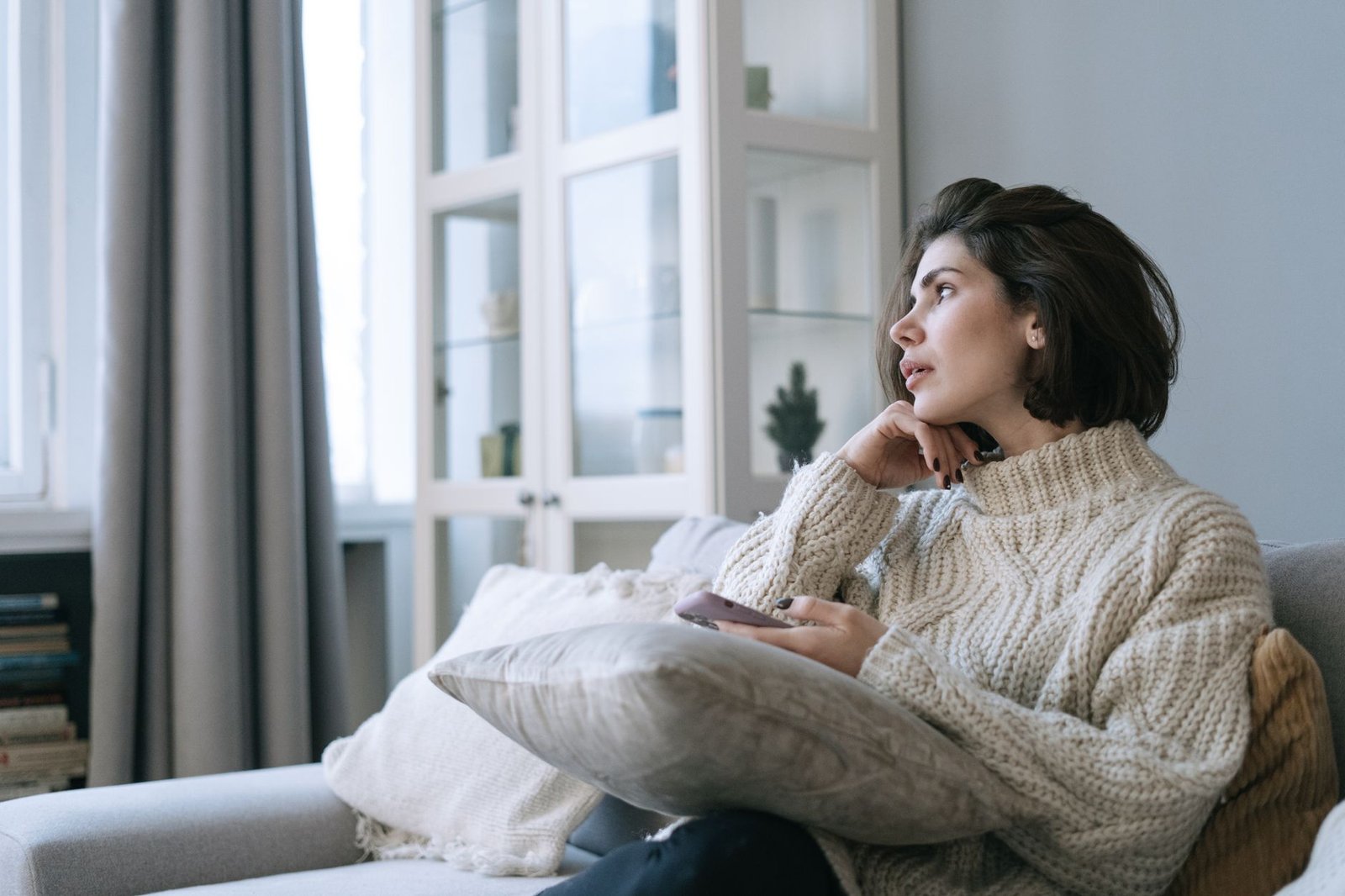 Woman on the couch holding her phone, processing difficult news
