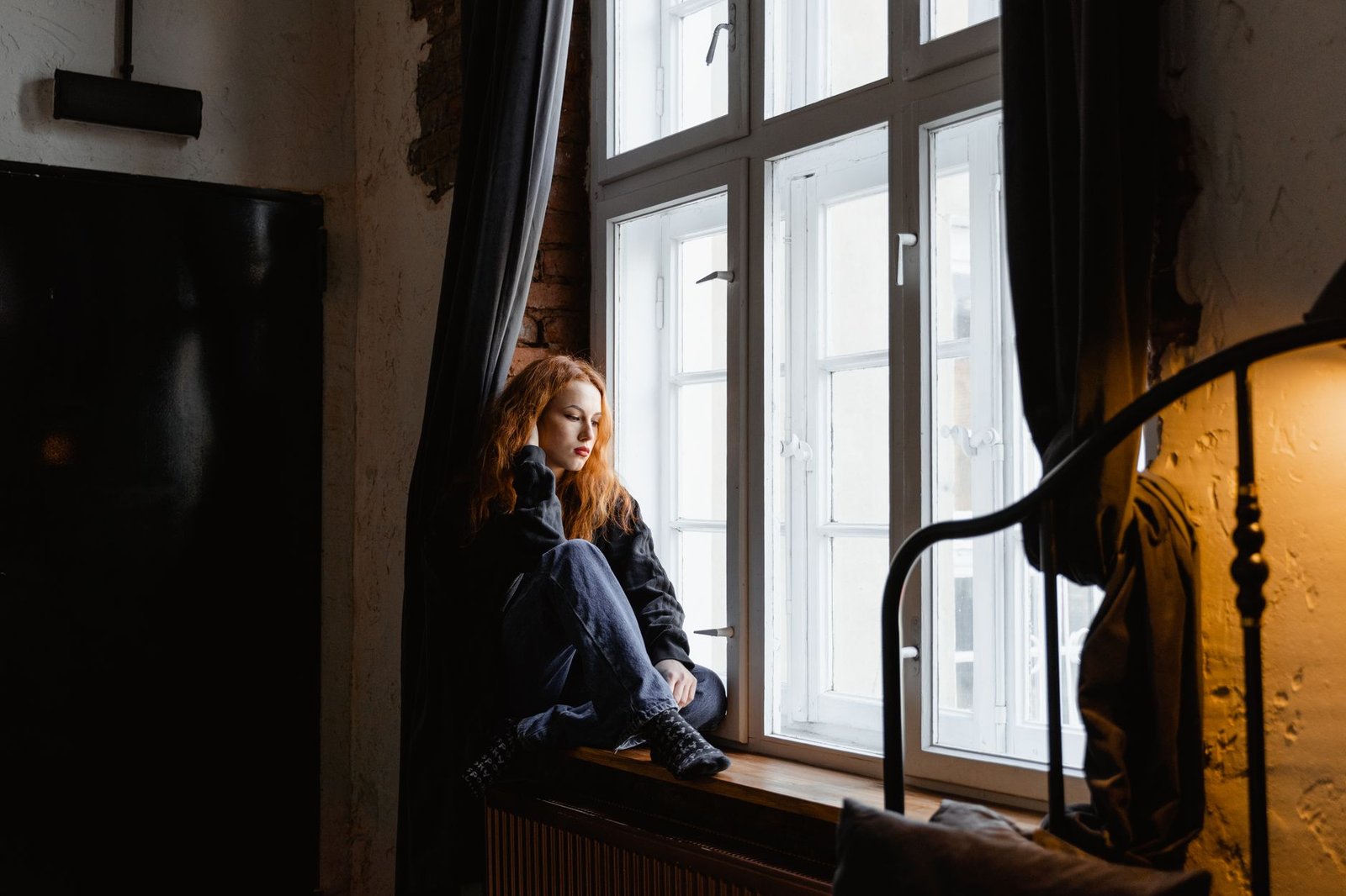 Woman sitting by a window thinking after a long distance argument