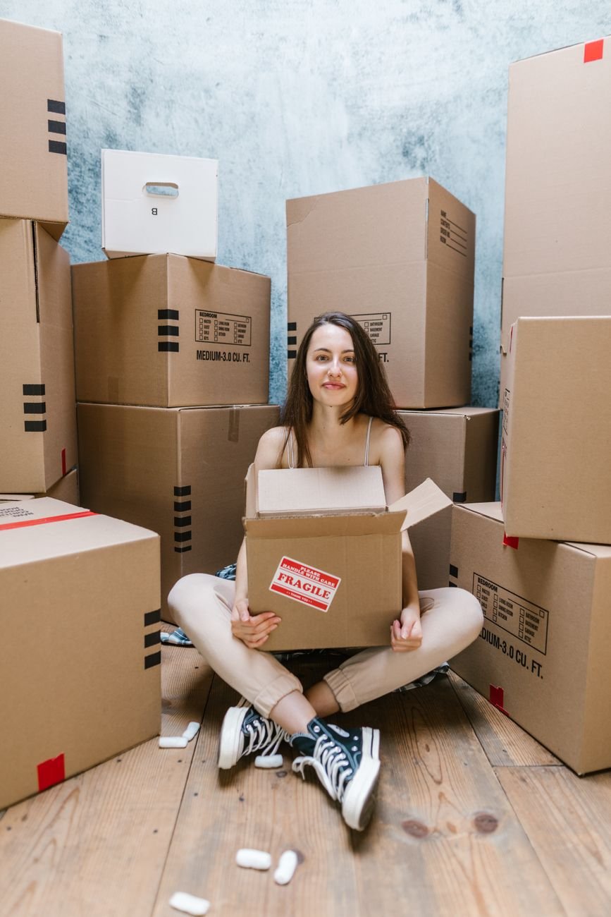 Woman sitting among moving boxes thinking about relocating