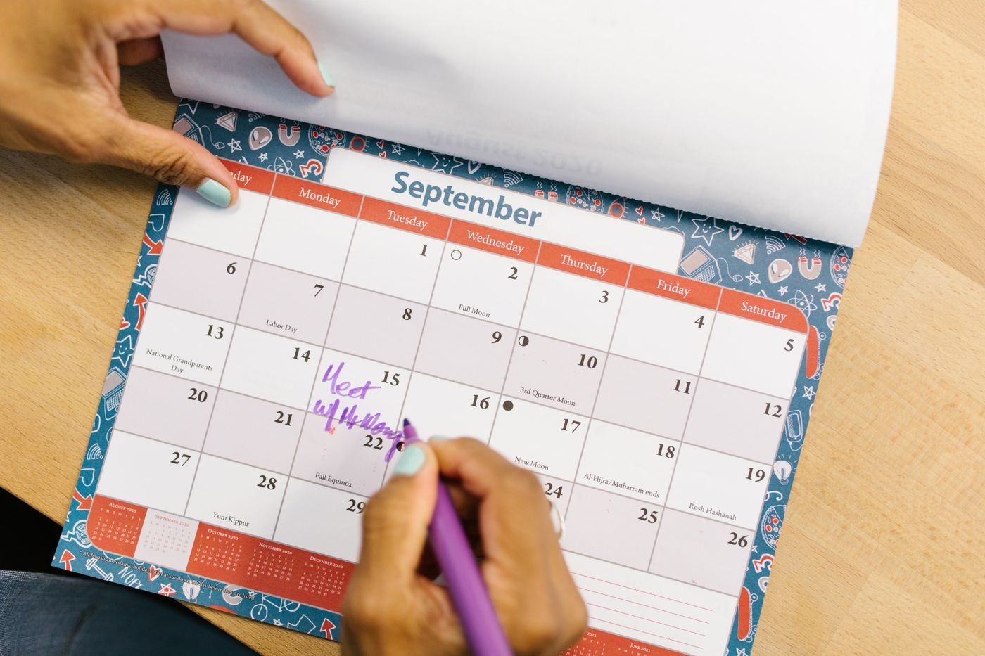 Hand marking a September date on a desk calendar to plan a long distance relationship timeline
