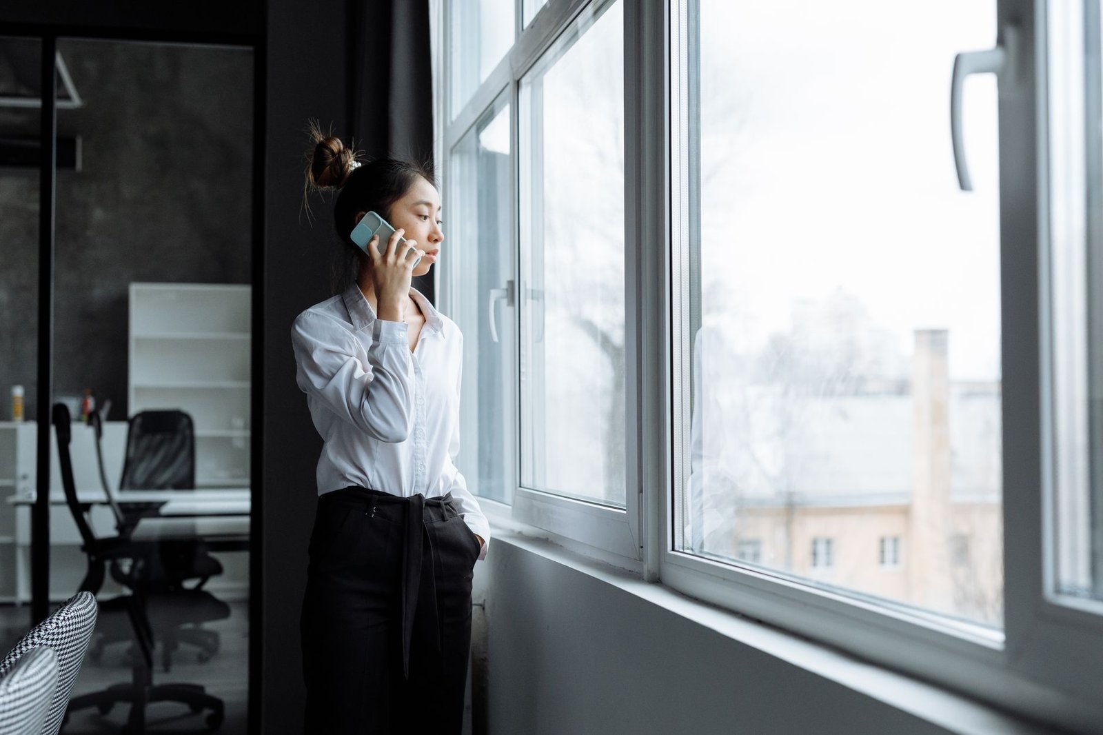 woman holding phone by a window feeling jealousy in a long distance relationship