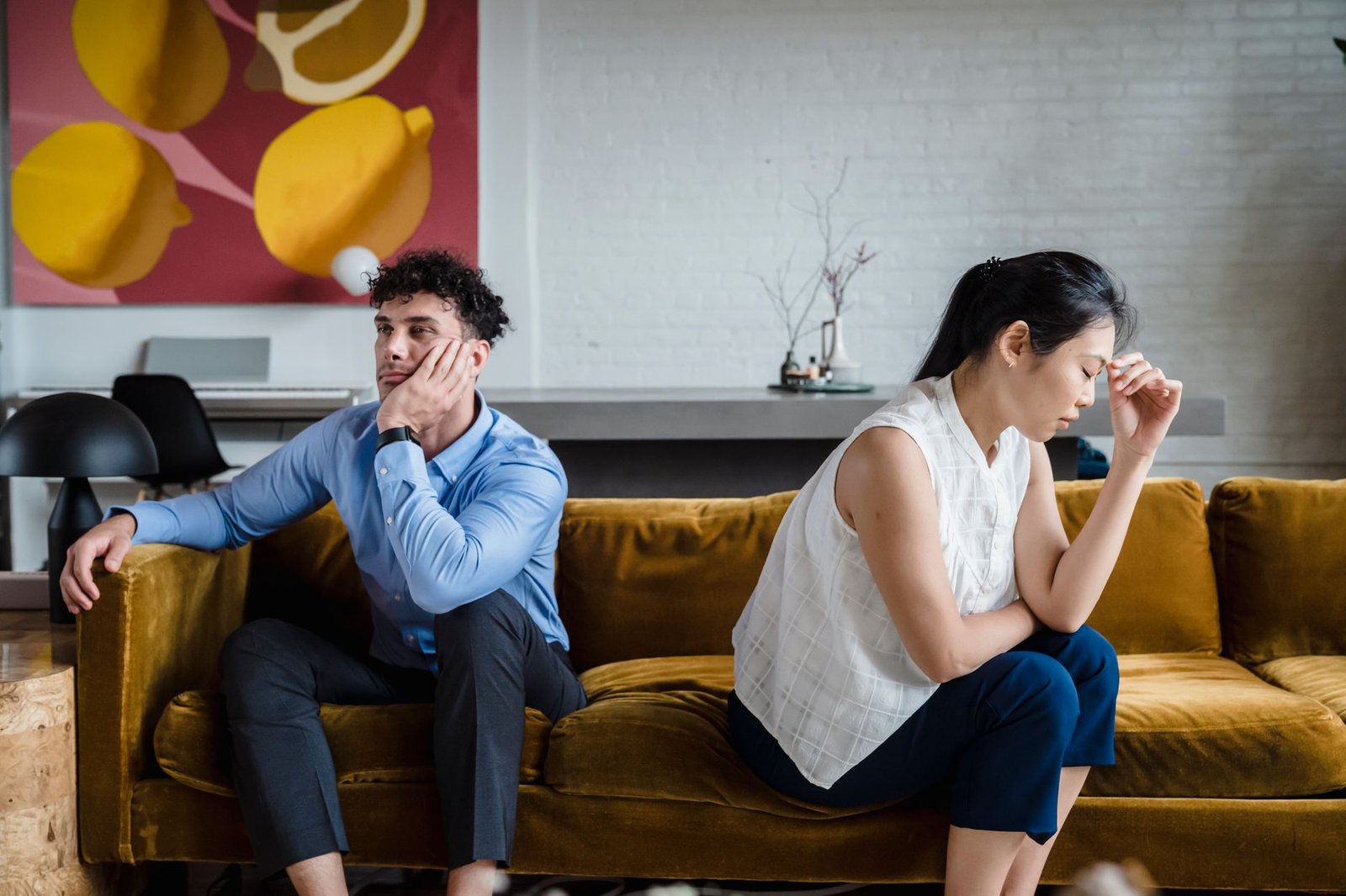 A couple sitting apart on a sofa after a phone created distance and mistrust between them
