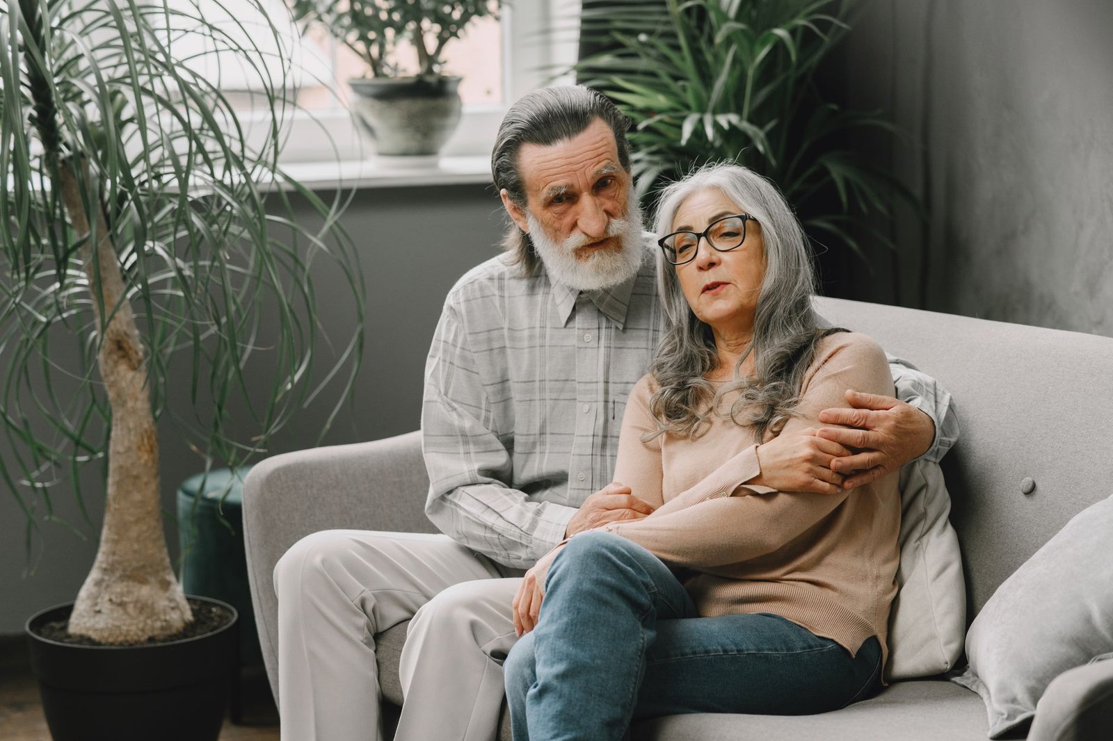 Couple embracing warmly on a sofa surrounded by plants