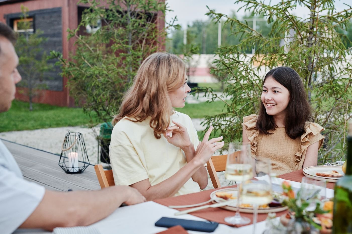 Family talking around an outdoor dinner table where long distance dating comes up