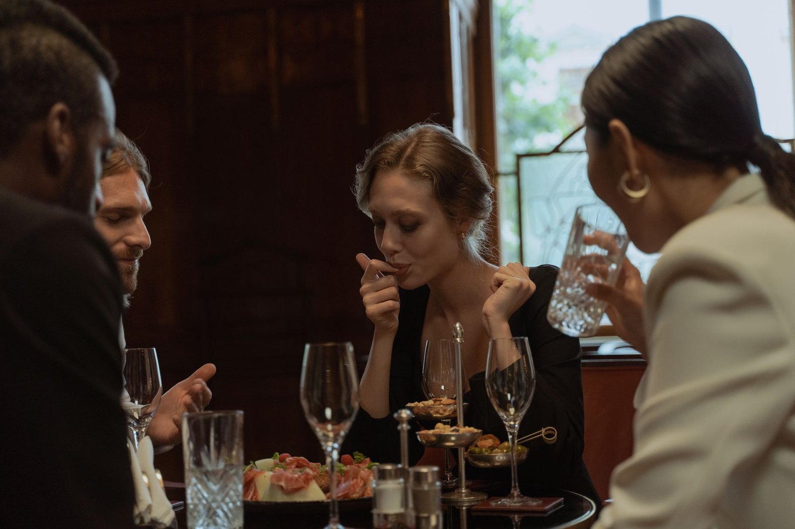 A group of friends laughing around a dinner table after a breakup splits a shared friend group