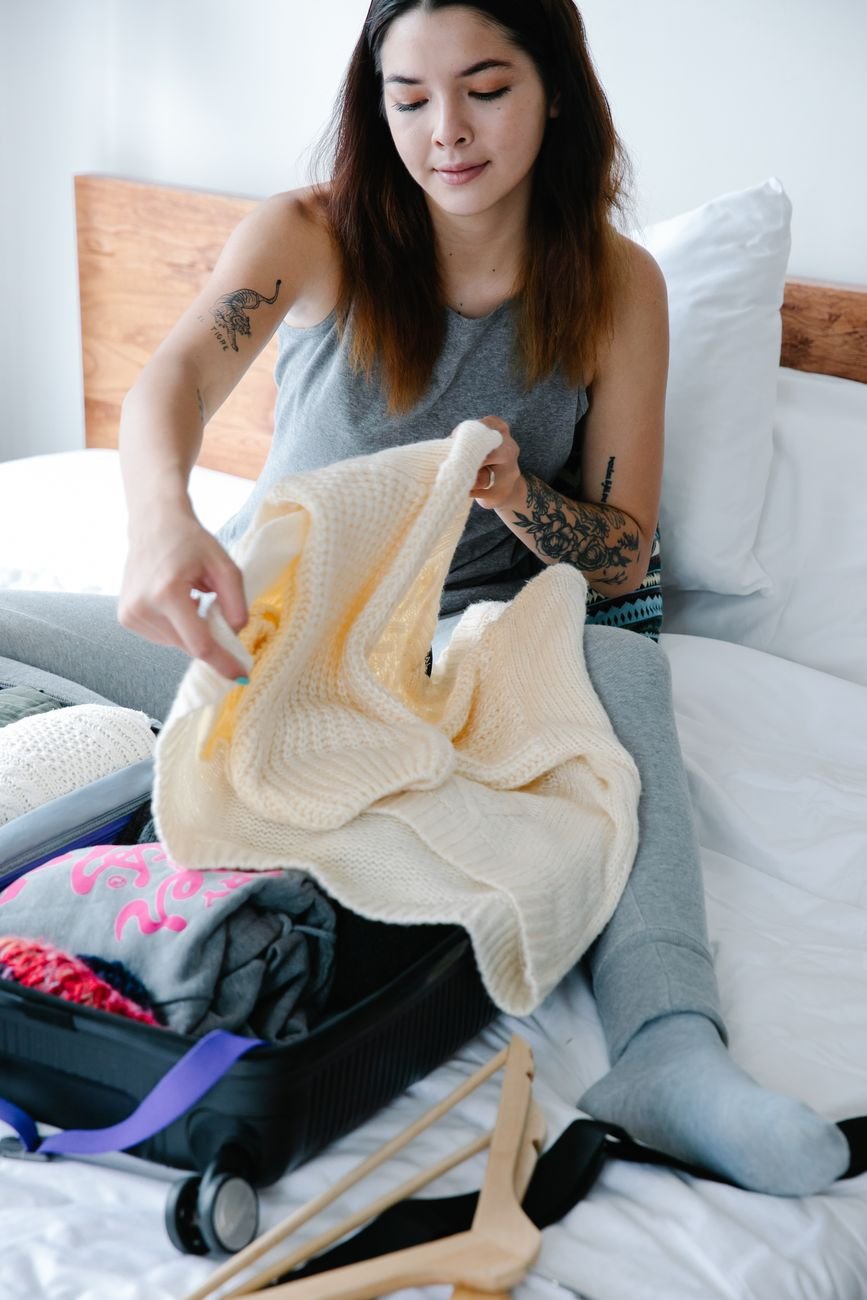 Woman organizing a suitcase on her bed while packing for a long distance relationship visit