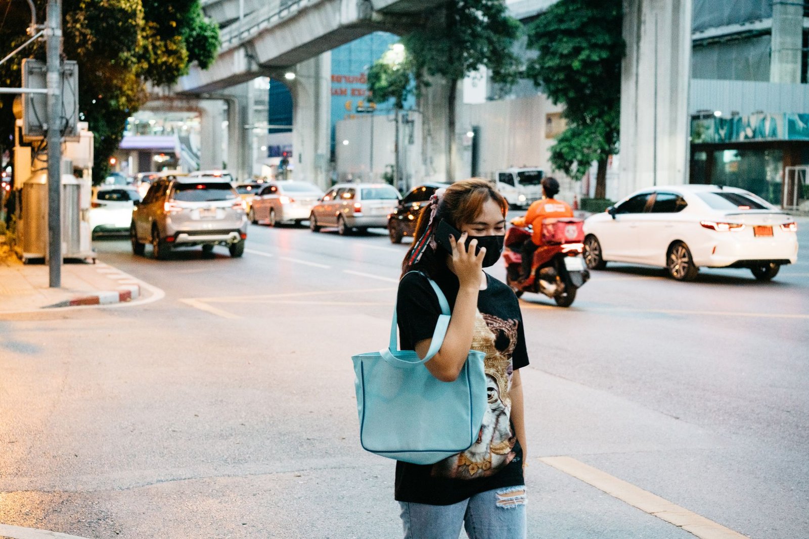 Woman sitting in her car at dusk holding her phone while waiting for a long distance call after daylight saving time
