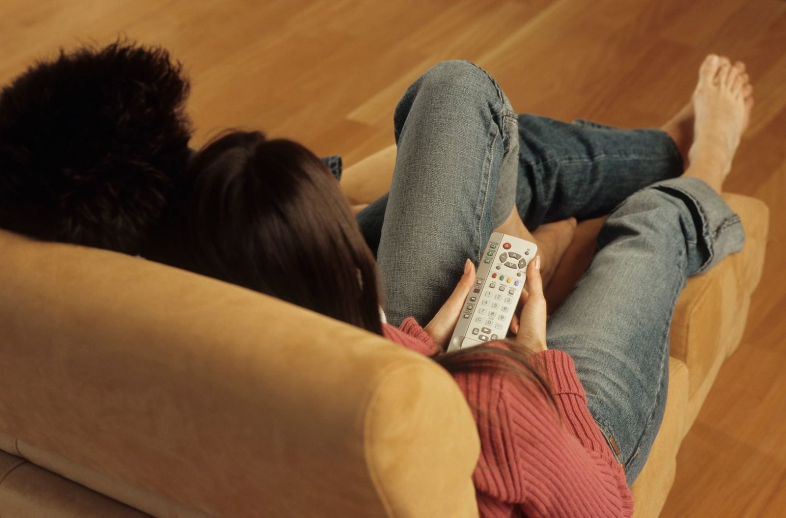 Couple sitting on a couch watching television with distance between them