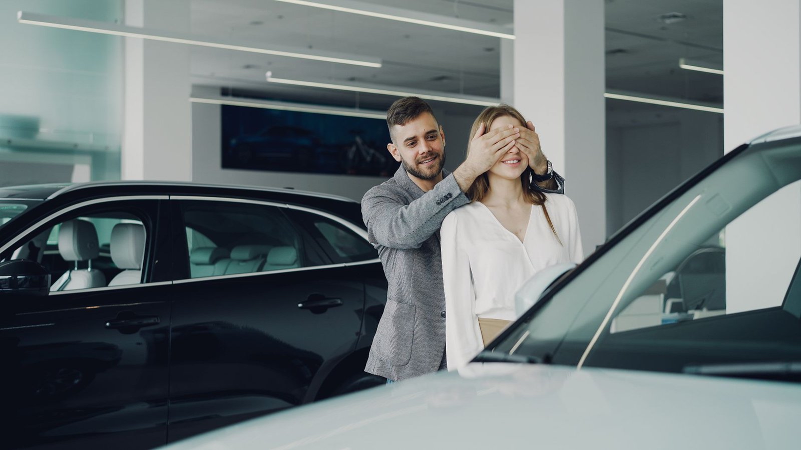 Smiling boyfriend covering his girlfriend's eyes for a surprise, a moment that is hard when you hate surprises