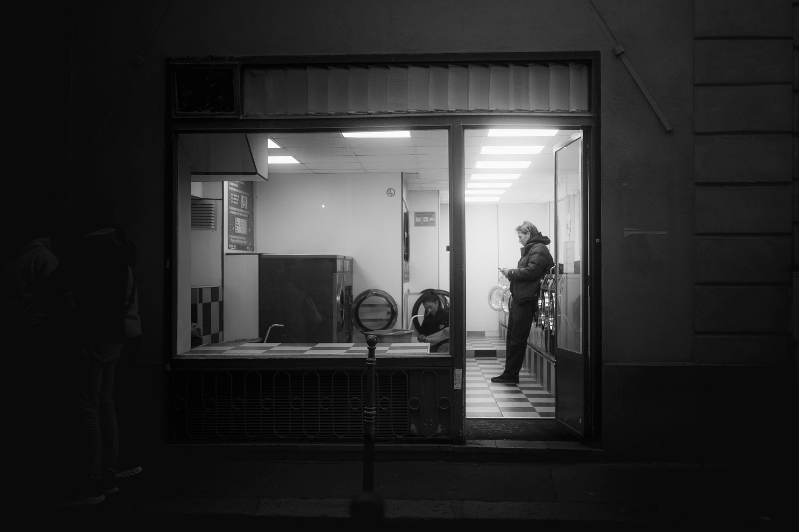 Woman in a laundromat looking at her phone after her ex likes old photos