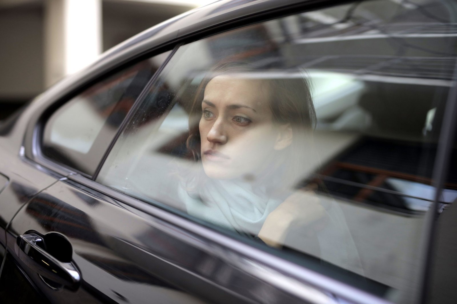 Woman gazing thoughtfully out a car window, lost in contemplation