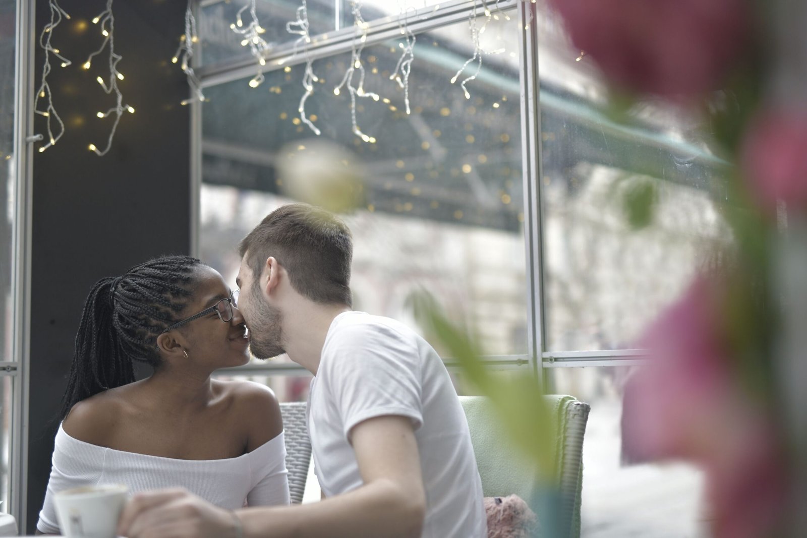Couple sharing a warm moment together at a cozy cafe with string lights