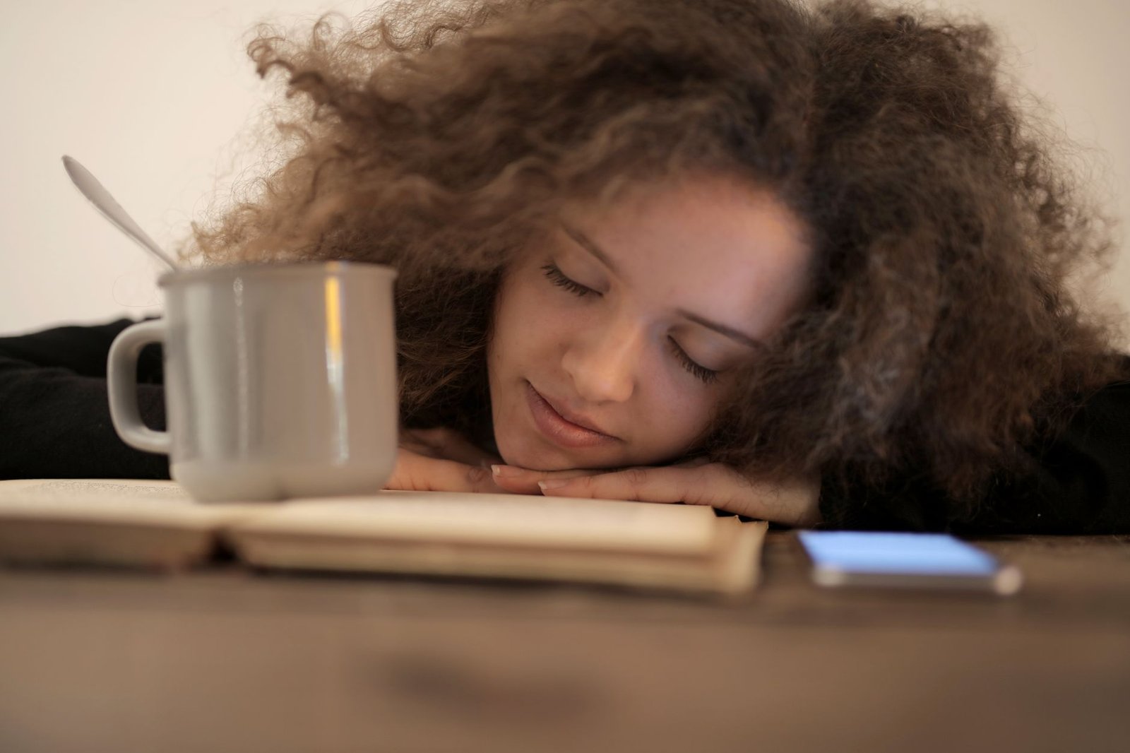 Phone lying face down on a table beside a coffee cup