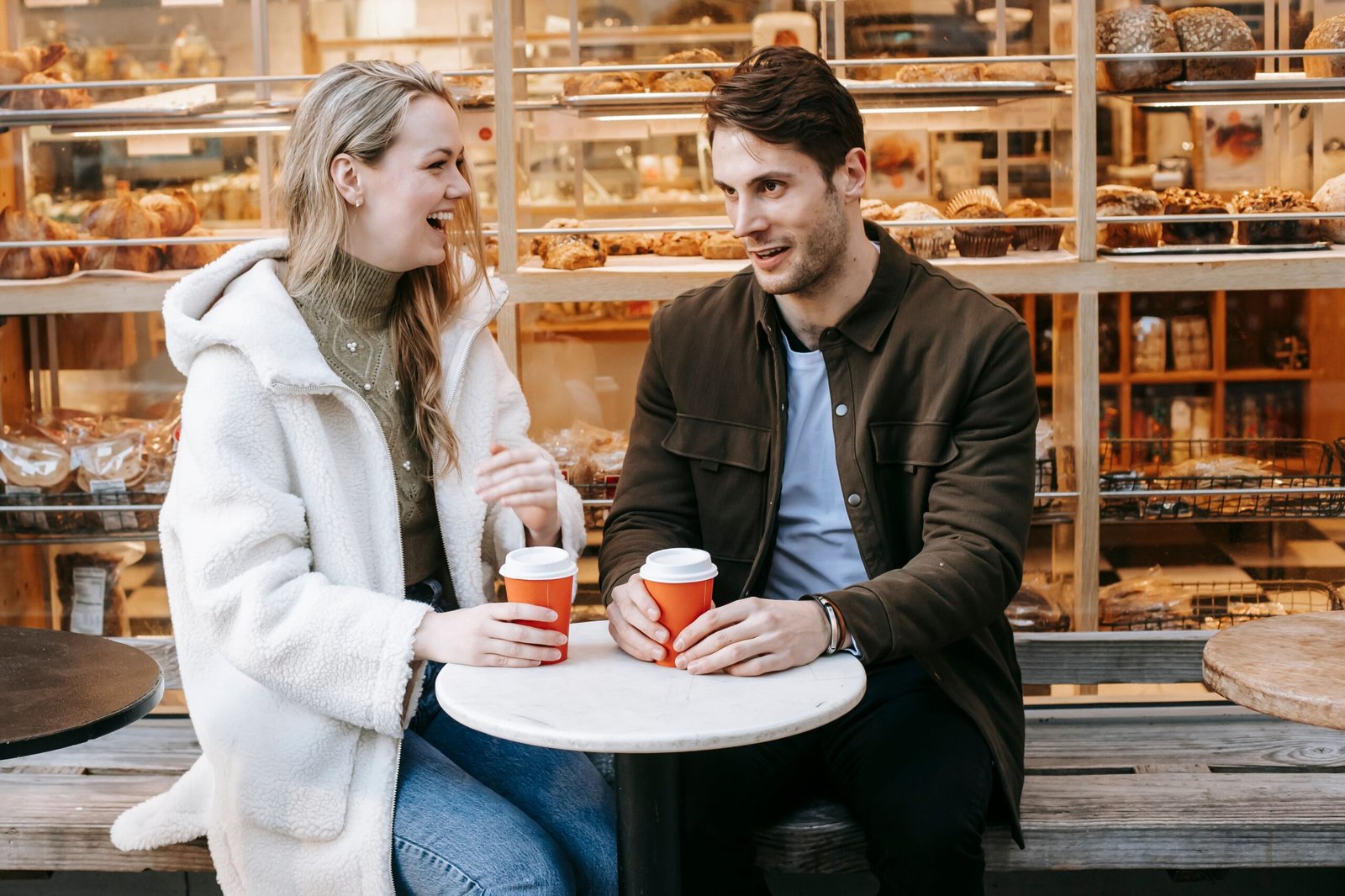 Couple laughing together on a bakery terrace during a first date