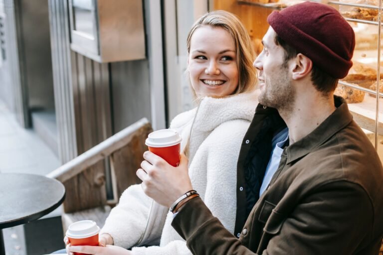 Couple smiling and enjoying coffee together on a first date at a cafe