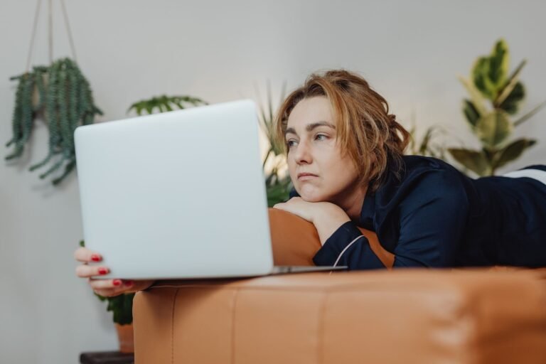 Woman staring at a laptop on the floor after failing an exam, unsure about failing in front of him