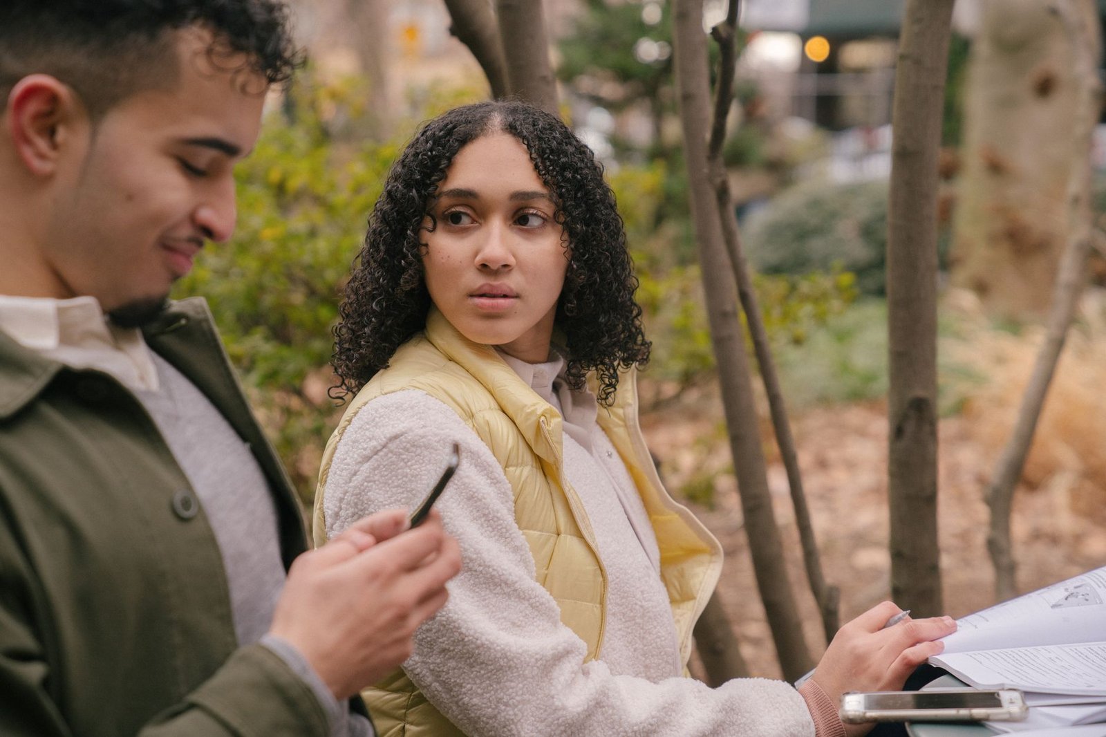 Woman watching her boyfriend from across a lawn, quietly feeling jealous