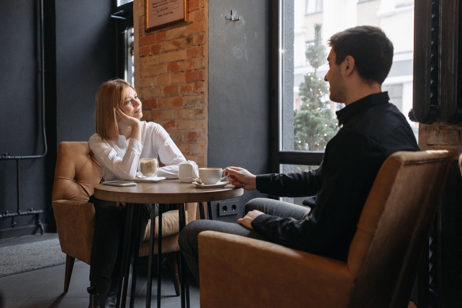 Couple enjoying coffee and conversation together by a cafe window
