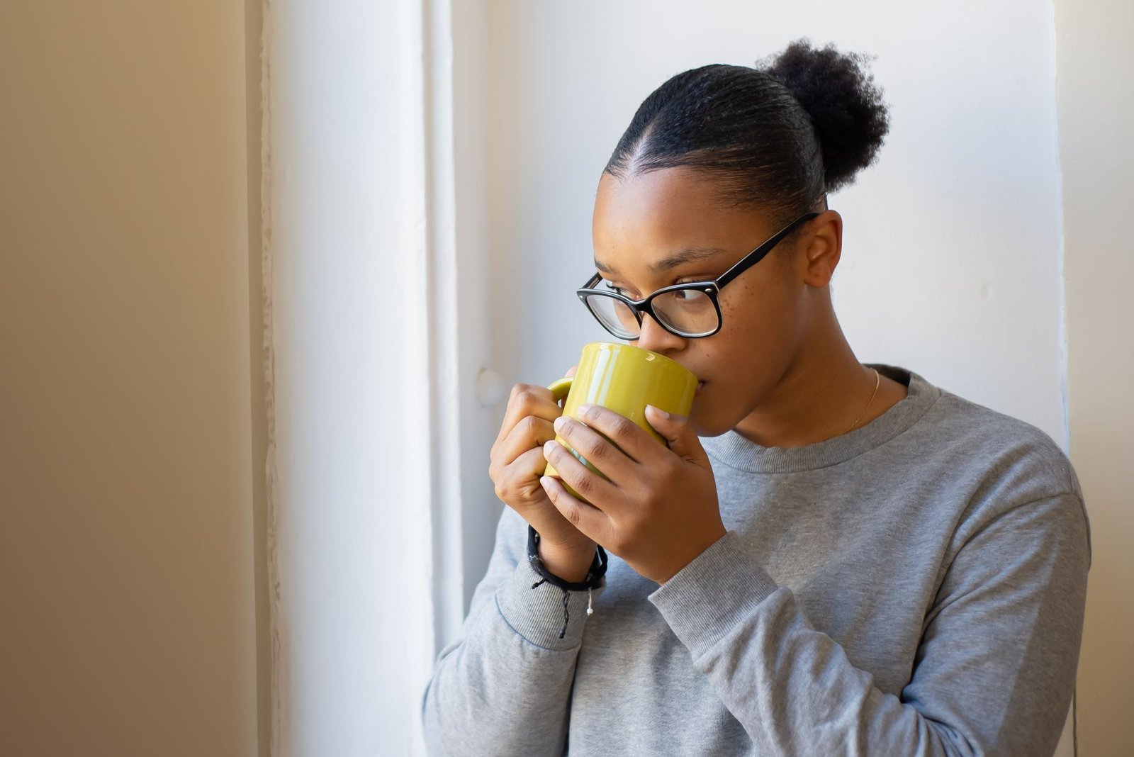 Woman drinking coffee from a new mug by a window