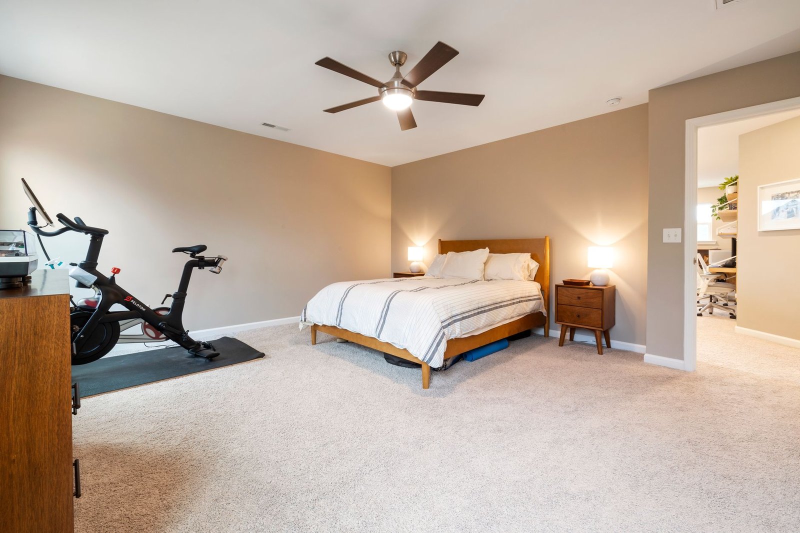 Small fan pointed at one side of a bed on a summer night
